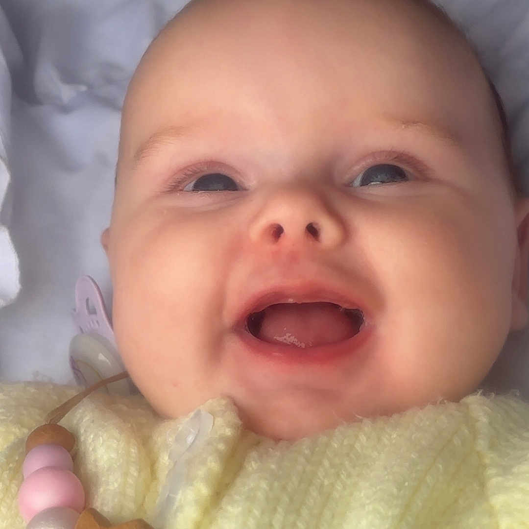 Romi is registered to the contest to win money with this photo: apparel, baby, beads, child, close_up, cute, expression, face, happy, head, indoors, infant, knitted, pacifier, portrait, skin, smiling, soft_light, wooden_star, yellow_clothing