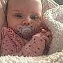 baby, pacifier, blanket, pink_clothing, polka_dots, infant, face, hands, cozy, soft_texture, indoor, portrait, cute, child, newborn, expression, comfort, closeup, warm, resting