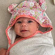 Malia a rejoint le concours — aidez-le/la à gagner de superbes lots ! baby, towel, hood, floral_pattern, ears, face, eyes, smile, hand, blanket, fabric, cute, infant, wrapped, soft, skin, portrait, indoor, colorful, person