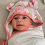 baby, towel, hood, floral_pattern, ears, face, eyes, smile, hand, blanket, fabric, cute, infant, wrapped, soft, skin, portrait, indoor, colorful, person
