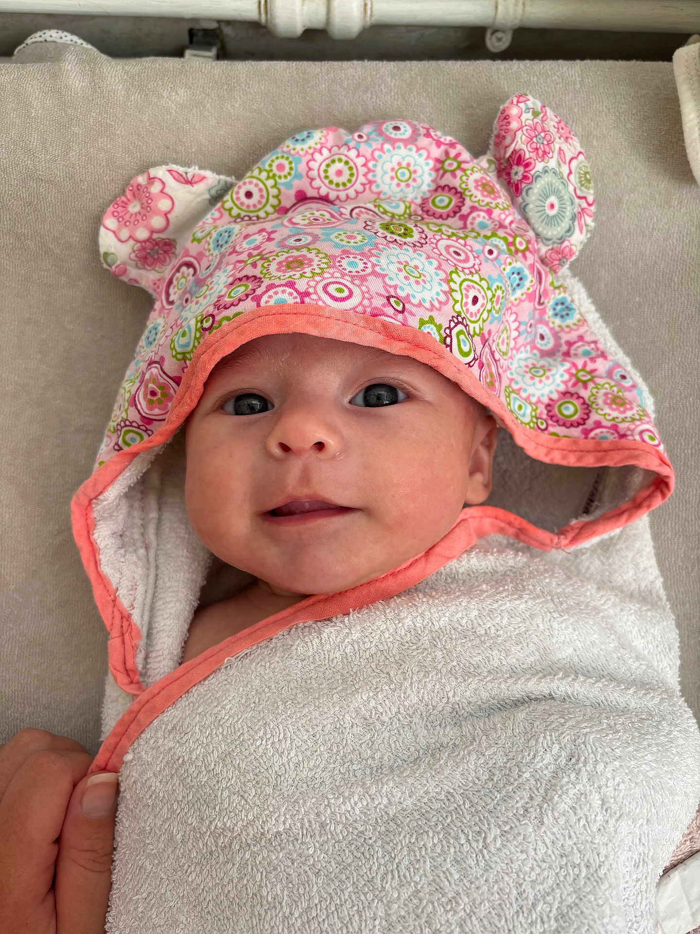Malia a rejoint le concours — aidez-le/la à gagner de superbes lots ! baby, towel, hood, floral_pattern, ears, face, eyes, smile, hand, blanket, fabric, cute, infant, wrapped, soft, skin, portrait, indoor, colorful, person