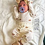 Nayeli is registered to the contest to win money with this photo: baby, infant, pacifier, headband, bow, blanket, clothing, onesie, footwear, soft_toy, pattern, crown, cute, lying_down, indoors, white_background, expression, newborn, warm, comfortable