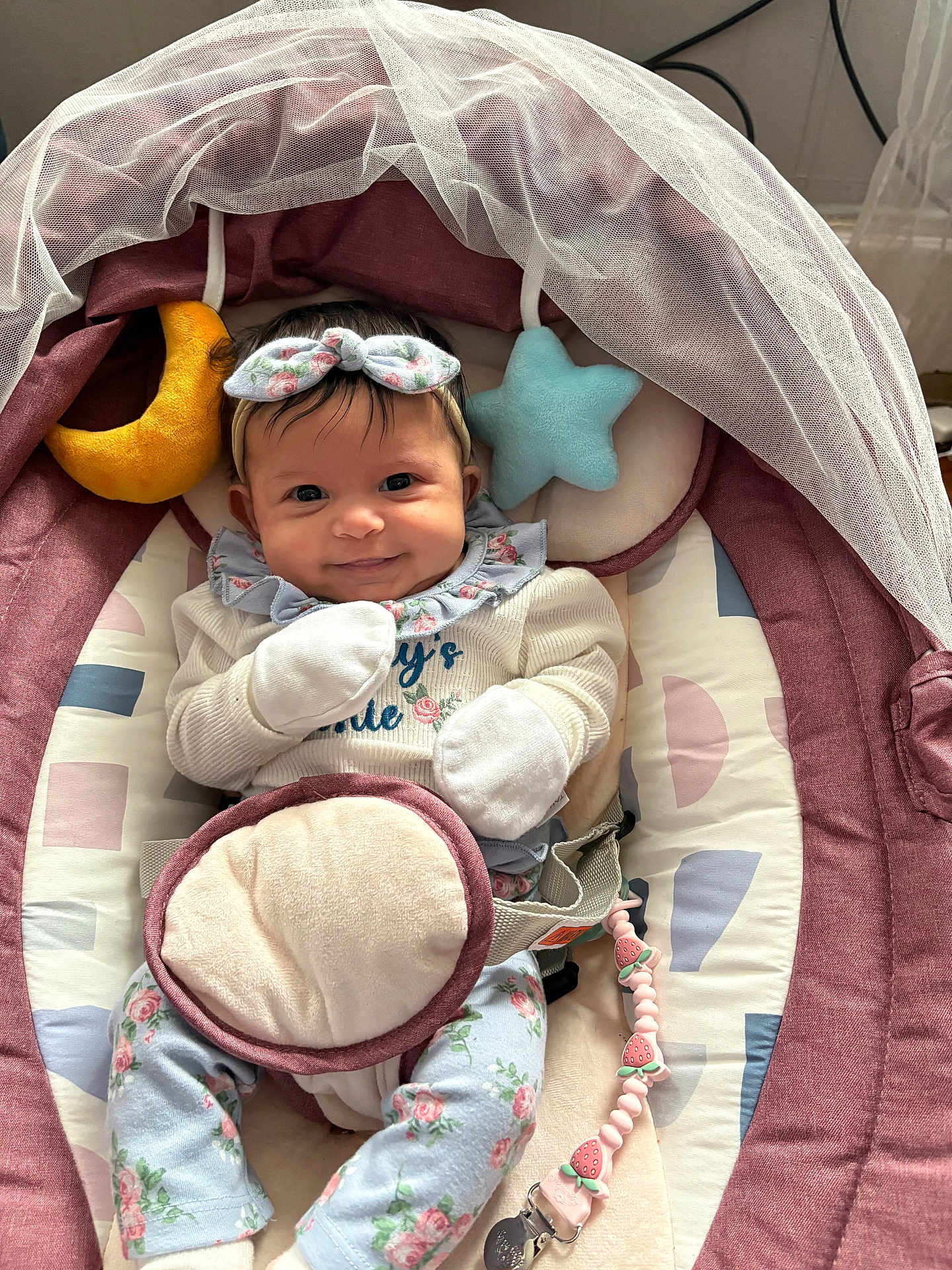 Nayeli is registered to the contest to win money with this photo: baby, infant, smile, headband, mittens, baby_seat, plush_toy, moon, star, floral_pattern, clothing, cute, indoor, child, person, soft_toys, fabric, comfort, happy, portrait