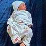 architecture, baby, bed, blanket, bonnet, building, cap, clothing, face, furniture, hat, head, hospital, newborn, pants, person, photography, portrait, quilt, sleeping