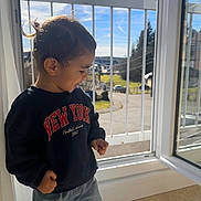 Batuhan a rejoint le concours — aidez-le/la à gagner de superbes lots ! child, toddler, sweatshirt, jeans, window, open_window, daylight, sunlight, indoor, balcony, railing, smiling, happy, casual_clothing, portrait, young_child, curly_hair, side_view, playing, home