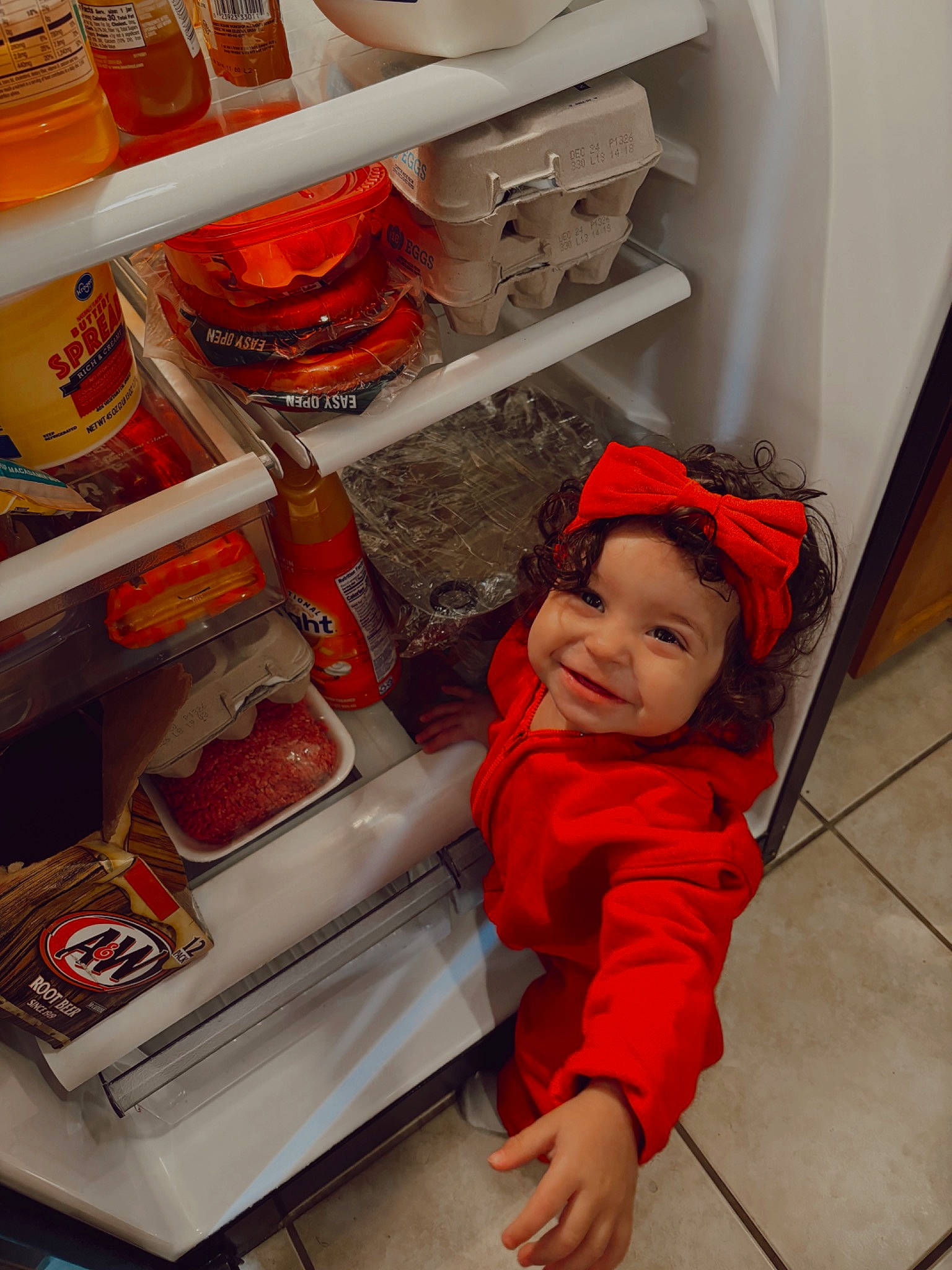 Alani is registered to the contest to win money with this photo: baby, baby_toddler_clothing, cooking, food, gas, headwear, home_appliance, hoodie, ingredient, joy, kitchen, kitchen_appliance, machine, major_appliance, orange, person, preserved_food, refrigerator, service, smile
