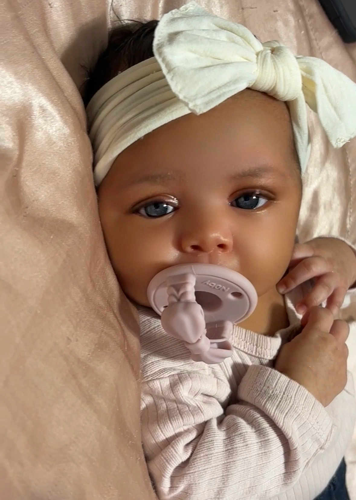 Leighton is registered to the contest to win money with this photo: baby, infant, pacifier, headband, bow, blue_eyes, close_up, blanket, soft_texture, cute, child, portrait, sleepwear, hands, face, skin, cozy, indoor, newborn, resting