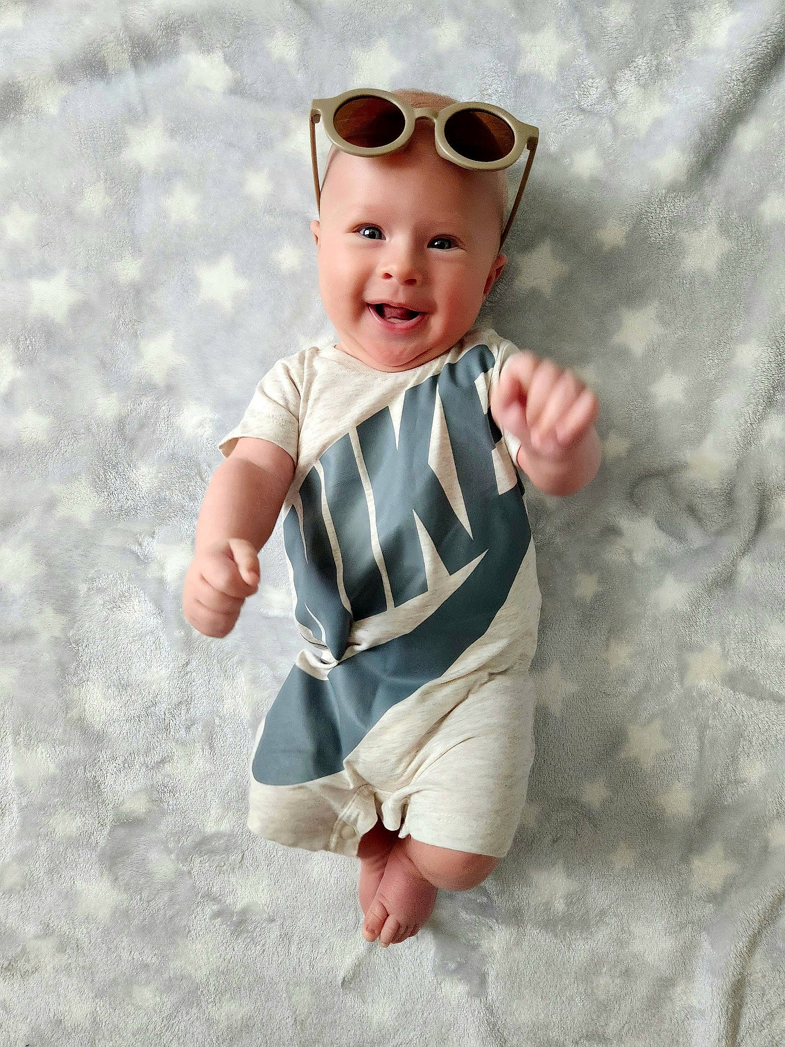 Darius is registered to the contest to win money with this photo: arm, baby, baby_toddler_clothing, chin, clothing, eyewear, face, facial_expression, gesture, glasses, goggles, hand, head, headwear, outerwear, person, skin, sleeve, smile, sunglasses