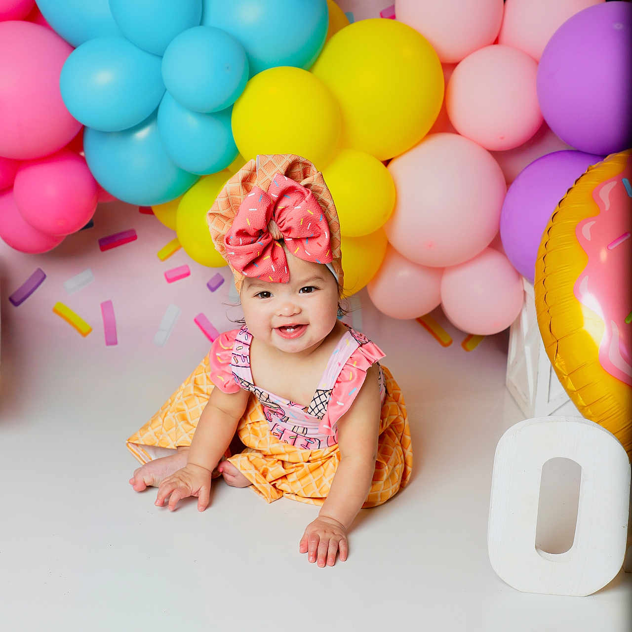 Crystal is registered to the contest to win money with this photo: baby, child, balloons, colorful, birthday, party, smiling, headband, bow, pink, blue, yellow, purple, ice_cream, outfit, floor, celebration, cute, happy, indoors
