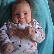 Marie participe au concours pour gagner de l'argent avec cette photo : baby, infant, smile, face, fist, blanket, clothing, animal_print, cozy, cute, lying_down, soft_texture, child, person, indoors, apparel, happy, young, portrait, sleepwear