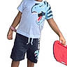 child, boy, dinosaur, tshirt, shorts, sneakers, toy, red, smile, standing, casual, playful, white_background, fashion, footwear, happy, accessory, short_hair, clothing, portrait