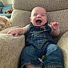 baby, infant, denim_overalls, laughing, smiling, armchair, furniture, cozy, indoor, person, child, cute, happy, sitting, dog, pet, living_room, couch, relaxing, home