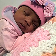 Sharlette joined the competition — help win amazing prizes! baby, sleeping, pink_clothing, hat, bow, blanket, knitted_blanket, closeup, face, child, cozy, soft_texture, indoors, peaceful, resting, cute, portrait, warm, infant, toddler