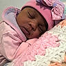 baby, sleeping, pink_clothing, hat, bow, blanket, knitted_blanket, closeup, face, child, cozy, soft_texture, indoors, peaceful, resting, cute, portrait, warm, infant, toddler