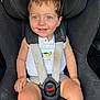 baby, blue_eyes, car_interior, car_seat, casual_clothing, child, cute, cute_expression, daylight, happy, infant, portrait, safety, seatbelt, secure, sitting, smile, toddler, white_shirt, young_child