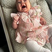 Aiyla joined the competition — help win amazing prizes! baby, infant, smiling, pink_dress, bow, cushion, patterned, lying_down, happy, cute, child, clothing, indoors, person, toddler, white_tights, furniture, closeup, portrait, small_hand