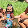 child, girl, water, stream, outdoor, summer, nature, grass, rocks, playing, happy, smiling, pigtails, shorts, tank_top, sunlight, people, adult, boy, fun