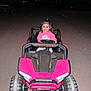 child, toddler, toy_car, pink, hoodie, night, headlights, gravel_road, smile, happy, outdoor, vehicle, small_wheels, dark_background, person, play, cute, portrait, driving, fun