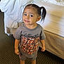Nallely joined the competition — help win amazing prizes! toddler, child, person, indoor, carpet, bed, messy_bed, bag, clothing, tshirt, shorts, sneakers, hair, pony_tail, smile, cute, standing, room, furniture, floor