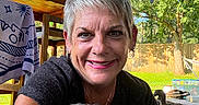 Theo Von is registered to the contest to win money with this photo: woman, smile, short_hair, pug, dog, pet, outdoor, backyard, wooden_patio, greenery, tree, fence, duck, animal, sunlight, happy, portrait, casual, earrings, tongue_out