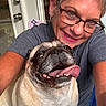 casual_clothing, closeup, dog, door, earrings, friendship, glasses, happy, indoor, joyful, pet, portrait, pug, seated, short_hair, skin, smiling, tattoo, tongue_out, woman