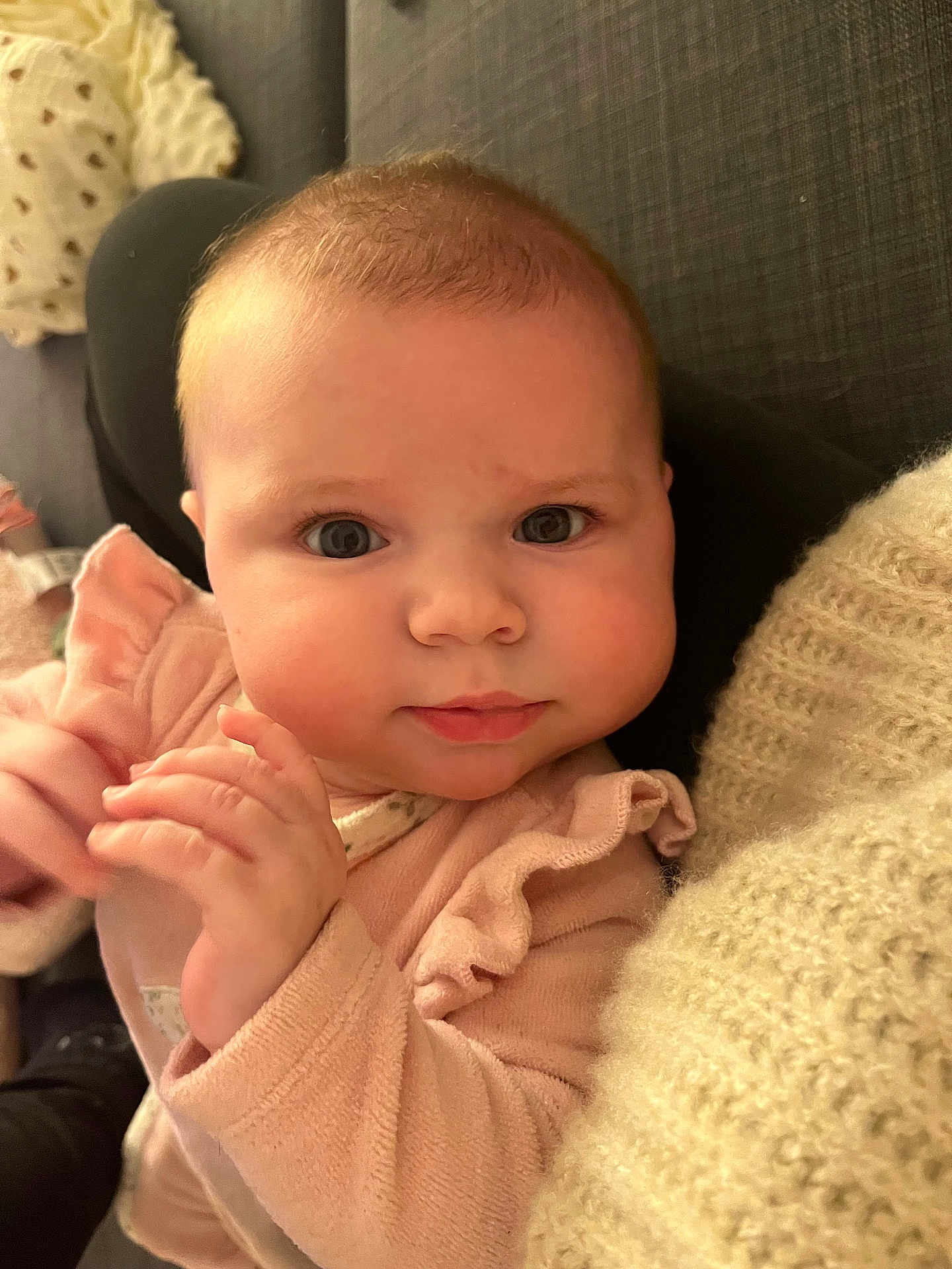 Alba a rejoint le concours — aidez-le/la à gagner de superbes lots ! baby, infant, child, face, hands, pink_clothing, ruffles, curious_eyes, chubby_cheeks, soft_texture, knit_blanket, cushion, indoor, portrait, cute, young_child, person, close_up, skin, expression