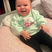 Alba a rejoint le concours — aidez-le/la à gagner de superbes lots ! baby, smiling, child, indoor, cushion, clothing, sitting, happy, face, pastel, sweater, black_pants, pattern, cozy, comfort, cheeks, person, cute, joy, warm_lighting