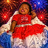 baby, child, tutu, red_clothing, blue_clothing, white_clothing, fireworks, celebration, holiday, 4th_of_july, festive, cute, smiling, portrait, sitting, curly_hair, star_pattern, colorful, background, happy