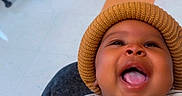 Tayvion Davis joined the competition — help win amazing prizes! baby, child, infant, smiling, laughing, portrait, close_up, knit_hat, striped_shirt, dog_design, clothing, sitting, indoor, office, chair, floor, colorful_tiles, home, happy, face