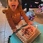 Cataleya joined the competition — help win amazing prizes! child, birthday_cake, candle, tongue_out, celebration, toy, blanket, floor, person, table, sweater, indoor, happy, smiling, party, young_child, playful, home, light, fun