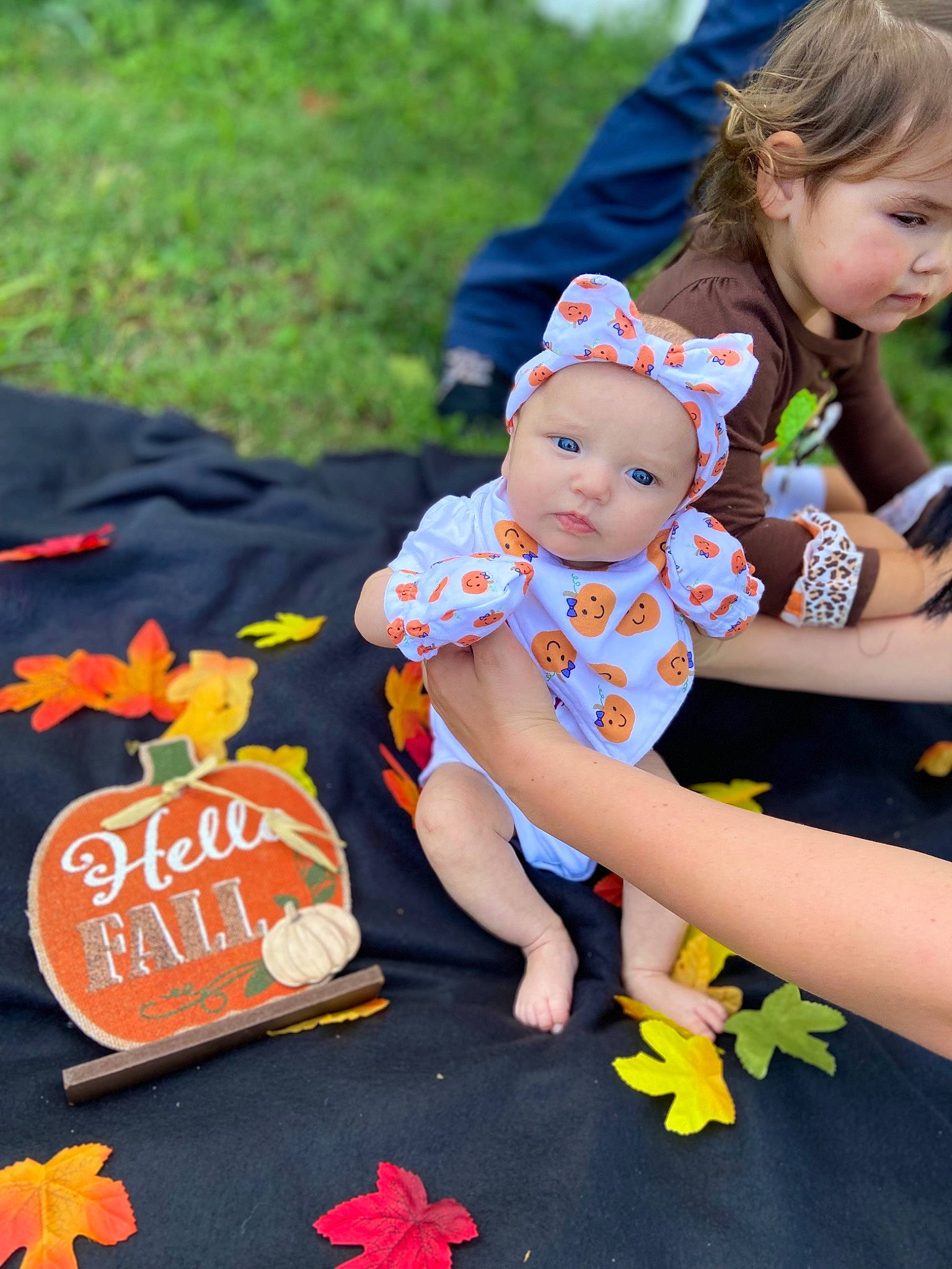 Emerie is registered to the contest to win money with this photo: baby, baby_toddler_clothing, child, dress, event, fun, grass, handwriting, happy, headwear, leaf, leisure, orange, person, pink, plant, recreation, red, sandal, sitting