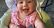 Charlotte joined the competition — help win amazing prizes! baby, child, smiling, hat, white_hat, pink_dress, indoor, toy, baby_seat, green_seat, happy, face, hand, carpet, table, person, infant, cute, colorful_toy, portrait