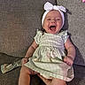 baby, child, couch, cozy, cute, dress, green_dress, hand, happy, headband, indoor, infant, laughing, person, seated, smiling, sock, sofa, textured_fabric, white_bow