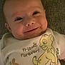 baby, infant, smiling, onesie, cartoon_print, simba, friends_forever_text, carpet, close_up, face, eyes, cheeky_smile, portrait, lying_down, clothing, cute, indoors, skin, young_child, happy