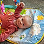 baby, infant, child, play_mat, toy, rattle, smile, carpet, onesie, colorful, panda_toy, cloud_pattern, lying_down, hand, eye_contact, indoors, cute, portrait, happy, closeup