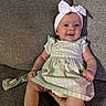 baby, bow, child, couch, cute, dress, girl, green_dress, hand, happy, headband, indoors, infant, person, portrait, sitting, smiling, sofa, textured_fabric, young_child
