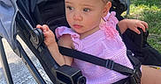 Autumn joined the competition — help win amazing prizes! toddler, child, stroller, pink_bows, pink_outfit, sitting, outdoor, daylight, greenery, road, sidewalk, baby, cute, curious, person, young_child, summer, sunlight, safety_harness, park