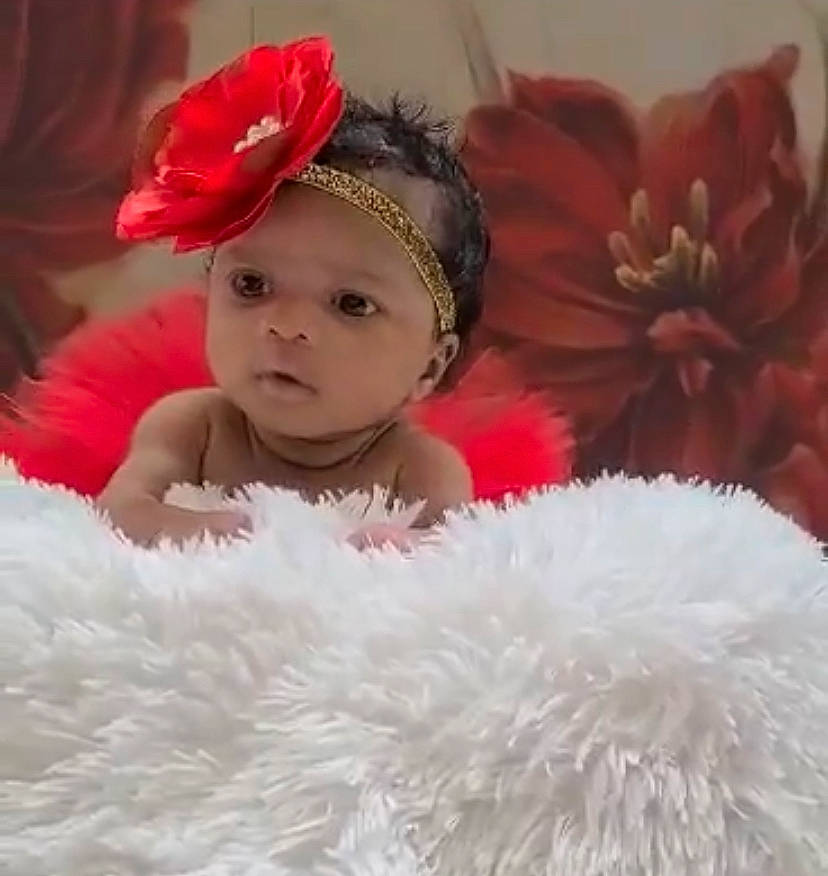 Kimora is registered to the contest to win money with this photo: baby, baby_toddler_clothing, cap, costume_hat, eyelash, face, finger, flower, fun, fur_clothing, happy, headband, headpiece, headwear, person, petal, pink, plant, red, skin