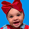 baby, child, infant, portrait, smiling, happy, red_bow, headband, blue_background, close_up, face, eyes, open_mouth, denim, overalls, red_clothing, floral_pattern, studio_photo, fashion, adorable
