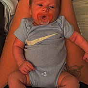 Chance is registered to the contest to win money with this photo: baby, infant, pacifier, blue_onesie, blue_socks, nike_logo, tattoo, legs, lap, person, skin, clothing, indoor, bed, blanket, cute, child, human, sitting, closeup