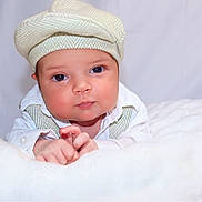 Lucas is registered to the contest to win money with this photo: baby, infant, face, hat, cap, clothing, white_shirt, suspenders, blanket, soft_texture, portrait, closeup, cute, child, resting, indoor, neutral_background, skin, hand, young
