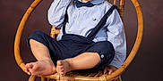 Jules Largeas participe au concours pour gagner de l'argent avec cette photo : toddler, child, boy, chair, wicker_chair, blue_shirt, bow_tie, suspenders, barefoot, portrait, studio, indoor, curious, sitting, brown_background, short_hair, cute, fashion, expression, person
