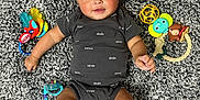 Kolson joined the competition — help win amazing prizes! baby, infant, child, carpet, toy, onesie, smile, face, person, lying_down, play, cute, cheerful, colorful_toys, soft_texture, indoors, skin, hands, feet, expression