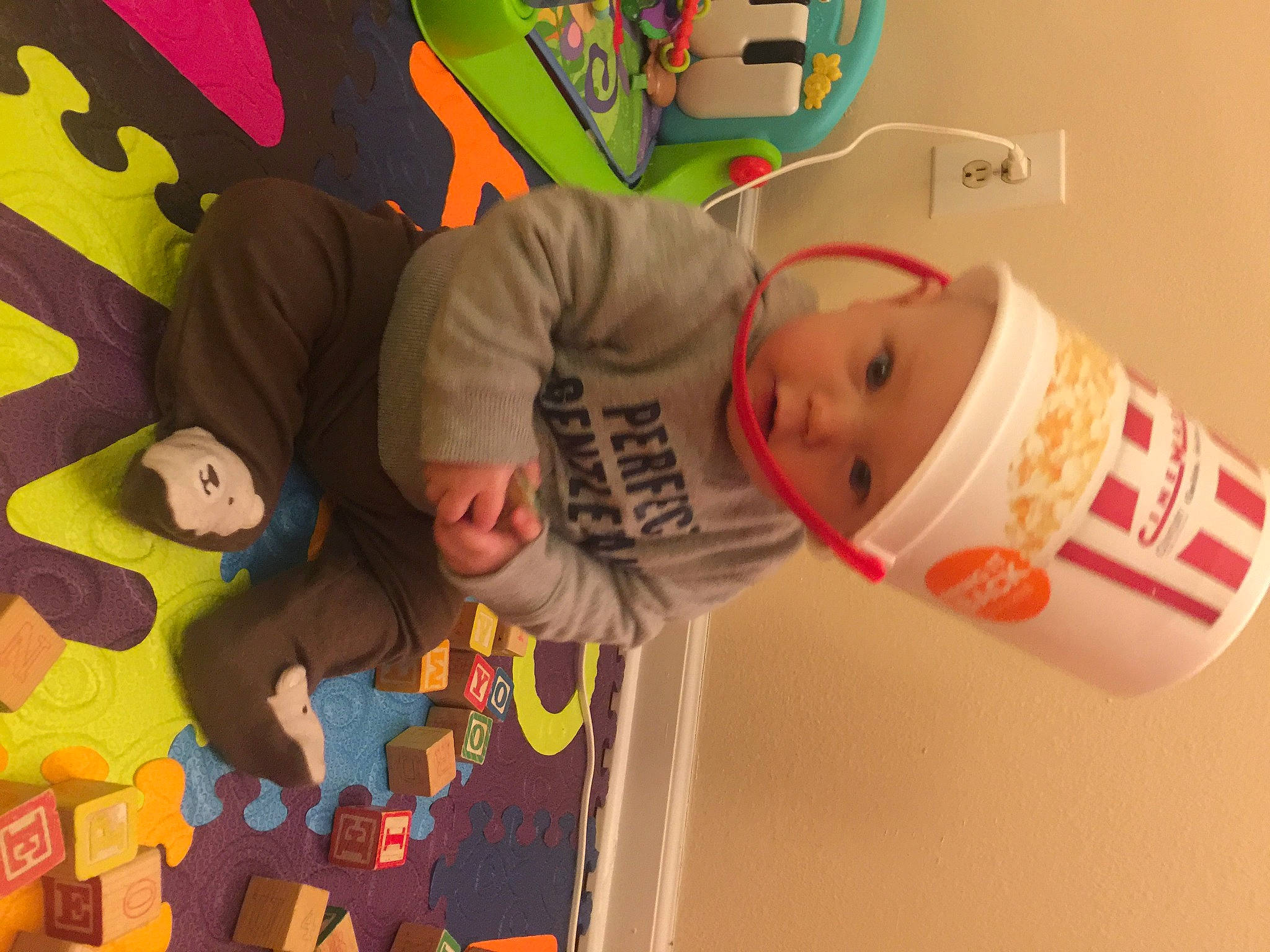 Gideon is registered to the contest to win money with this photo: animation, baby, baby_toys, child, event, facial_expression, finger, font, fun, happy, headwear, leisure, mammal, orange, person, play, product, room, t_shirt, toddler