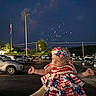 baby, child, patriotic, dress, headband, fireworks, night, parking_lot, car, american_flag, person, celebration, outdoor, holiday, cute, festive, holding_hands, sky, lights, people