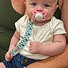 Marilyn joined the competition — help win amazing prizes! adult_arm, baby, child, closeup, clothing, cute, denim_shorts, expression, face, green_top, hand, holding, indoor, infant, pacifier, person, portrait, sitting, skin, watch