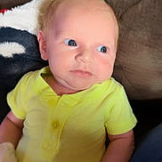 Kolter joined the competition — help win amazing prizes! baby, infant, yellow_clothing, mittens, couch, blanket, indoor, person, child, cute, newborn, portrait, sitting, soft_lighting, face, expression, young_child, comfortable, casual, home