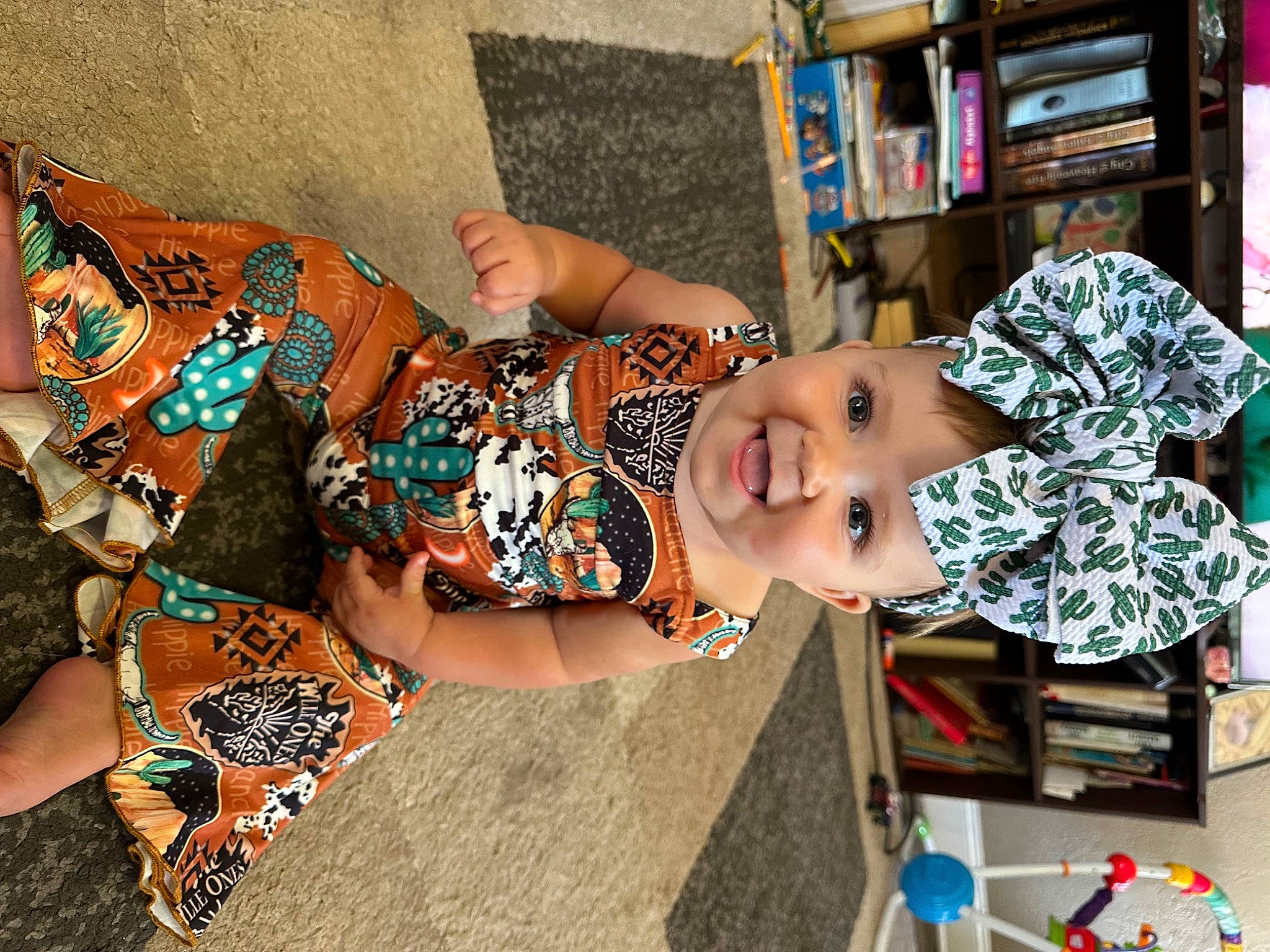 Saylor joined the competition — help win amazing prizes! baby, baby_toddler_clothing, bookcase, child, dress, fun, happy, headwear, house, human_leg, joy, leisure, pattern, person, play, room, shelf, shelving, thigh, toddler