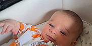 Leo is registered to the contest to win money with this photo: baby, infant, stroller, crab_pattern, clothing, cute, child, face, hand, paciifier, beads, orange, white, gray, indoor, person, newborn, sleeping_bag, toddler, portrait