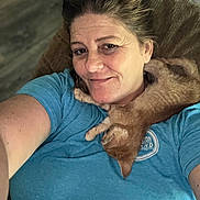 Miss Kitty is registered to the contest to win money with this photo: woman, smiling, selfie, kitten, cat, orange_tabby, pet, affection, indoor, blue_shirt, casual, relaxed, furniture, chair, hair, skin, portrait, comfort, resting, closeup